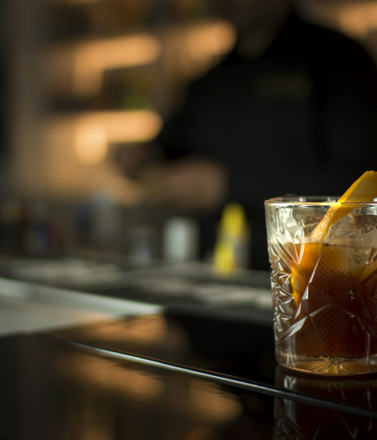 An old fashioned with an orange peel on the bar counter.