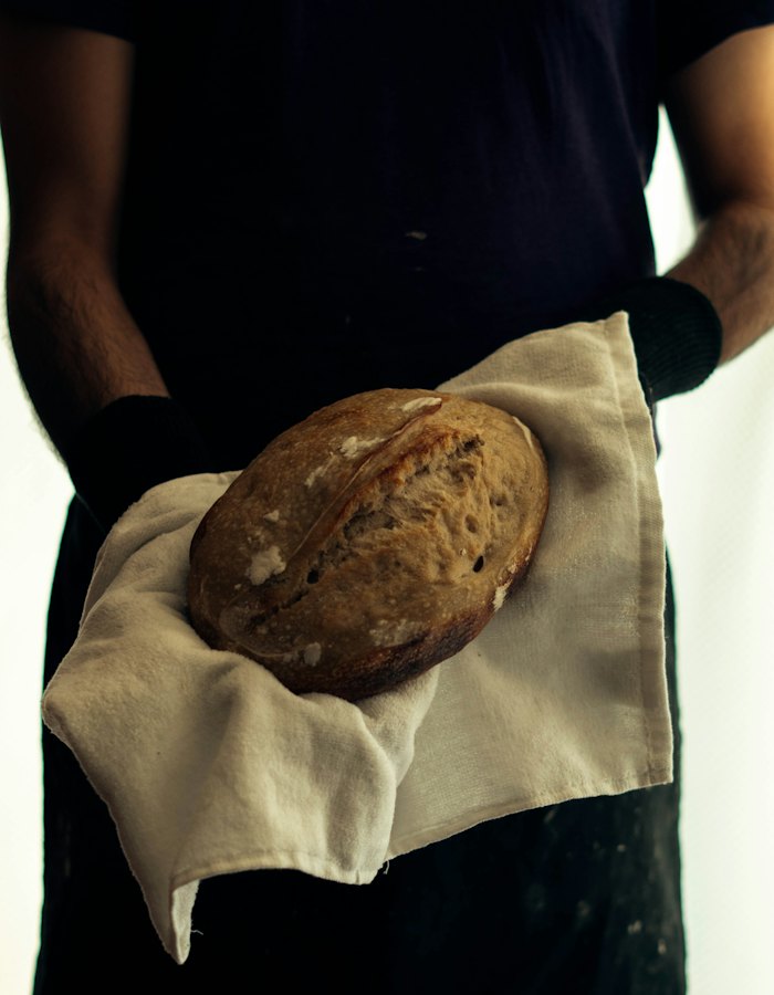 A baker holding a loaf wrapped in a linen cloth.