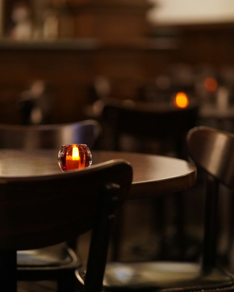 A candle burning on a table in the dark room.