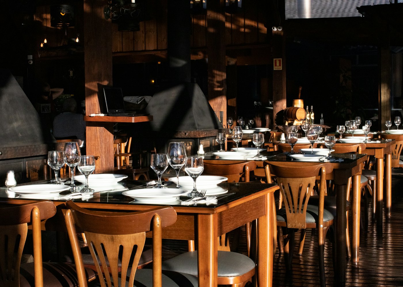 The dining room set for service: wooden tables, bentwood chairs, low light.